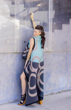 Load image into Gallery viewer, Woman wearing a patterned dress leaning against a glass wall.