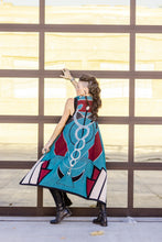 Load image into Gallery viewer, Woman wearing a colorful dress with abstract patterns standing against a glass wall.