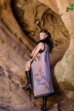 Load image into Gallery viewer, Woman in a long, patterned dress standing in a natural rock formation