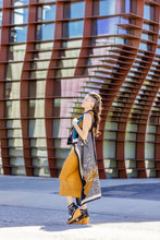 Load image into Gallery viewer, Woman holding a colorful scarf in front of a modern architectural background