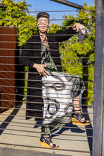 Load image into Gallery viewer, Person holding a black and white patterned bag outdoors