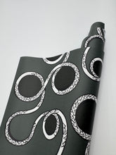 Load image into Gallery viewer, Black yoga mat with white snake design on a light gray background