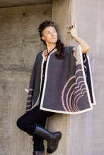 Load image into Gallery viewer, Woman wearing a patterned cape against a concrete wall