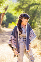 Load image into Gallery viewer, Woman in a patterned shawl standing outdoors with trees in the background