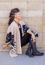 Load image into Gallery viewer, Woman wearing a patterned shawl and knee-high boots against a stone wall.
