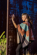 Load image into Gallery viewer, Person wearing a patterned poncho against a textured wall