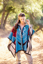 Load image into Gallery viewer, Woman wearing a colorful poncho with a geometric pattern in a natural setting
