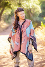 Load image into Gallery viewer, Woman wearing a patterned poncho outdoors with trees in the background