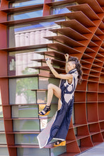 Load image into Gallery viewer, Woman taking a selfie against a modern architectural wall with geometric patterns.
