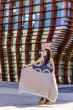 Load image into Gallery viewer, Woman holding a large patterned scarf in front of a modern building
