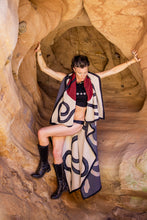 Load image into Gallery viewer, Person wearing a patterned shawl in a rocky cave
