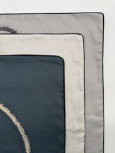 Load image into Gallery viewer, Close-up of a folded fabric with geometric patterns on a white background
