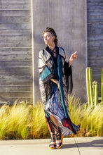 Load image into Gallery viewer, Woman in a colorful dress standing outdoors with cacti and grasses in the background

