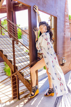 Load image into Gallery viewer, Woman in a patterned dress standing on a staircase outdoors
