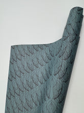 Load image into Gallery viewer, Roll of blue fabric with black leaf pattern on a white background
